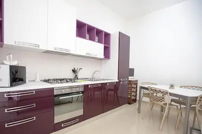 a kitchen with purple cabinets and a table with chairs at Casa in centro in Castellammare del Golfo