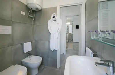 a bathroom with a white robe hanging on the wall at ITACA e MEDEA - Appartamenti con idromassaggio in terrazza in San Vito lo Capo