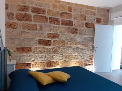 a brick wall with a blue bed with yellow pillows at Bed and Breakfast Stella del Sud Makari in Macari