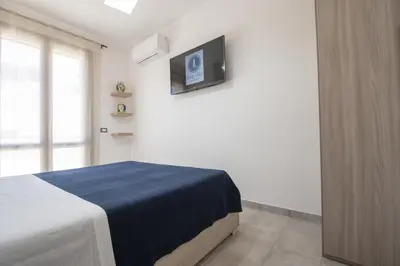 a bedroom with a bed and a tv on the wall at Sea Vito Apartment in San Vito lo Capo