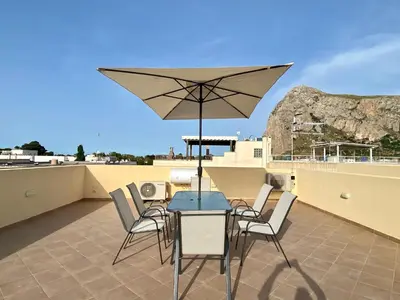 a table with chairs and an umbrella on a roof at Sea Vito Apartment in San Vito lo Capo