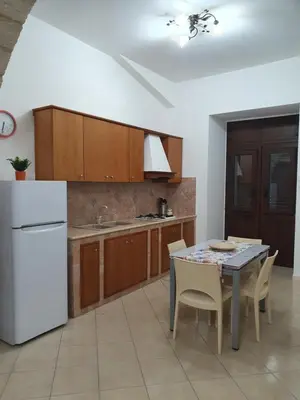 a kitchen with a table and a white refrigerator at Casa vacanza Corallo in Castellammare del Golfo