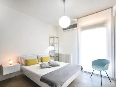 a white bedroom with a bed and a blue chair at Villa Re di Denari by Interhome in Terrasini