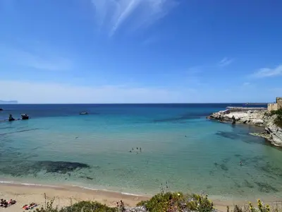 a beach with people swimming in the water at Villa Re di Denari by Interhome in Terrasini