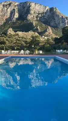 a large swimming pool with a mountain in the background at Villa dell’Orsa in Cinisi