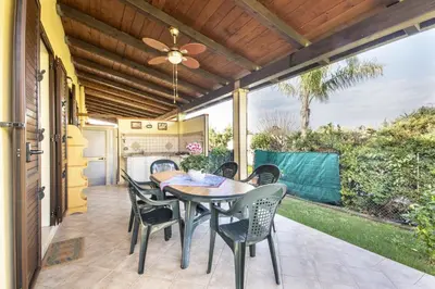 a patio with a table and chairs and a ceiling fan at Case Vacanze Paradise Beach Vicino Cefalù PISCINA APERTA in Campofelice di Roccella