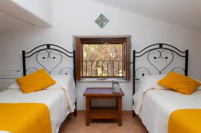 two beds in a room with a window and a table at Feudo Giglio Country Charme in Calatafimi