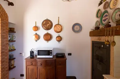 a kitchen with a microwave on a wooden cabinet and plates on the wall at Feudo Giglio Country Charme in Calatafimi