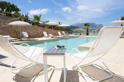 two chairs and a table in front of a swimming pool at Feudo Giglio Country Charme in Calatafimi