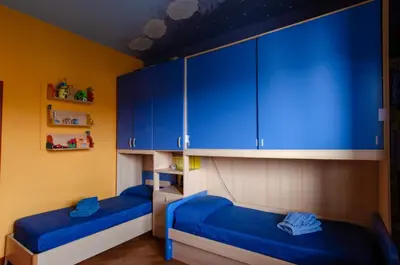 two beds in a room with blue cabinets at POLICLINICO HOME in Palermo