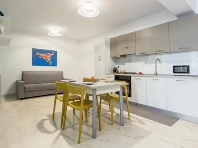 a kitchen and living room with a table and chairs at Azzurra Apartments in Balestrate