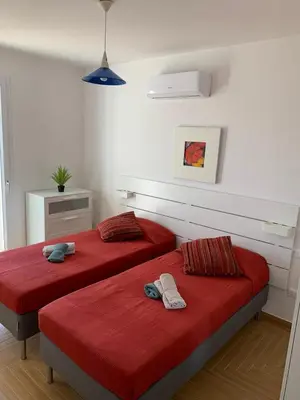 two beds in a white room with red sheets at Le Case Vacanze di Federico in Terrasini