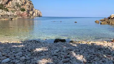 a rocky beach with people swimming in the water at Le Case Vacanze di Federico in Terrasini