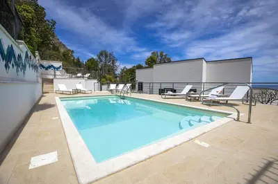 a swimming pool with chairs and a building at Kafara Resort- Villas and Pool by Lisca Bianca Rental in Santa Flavia