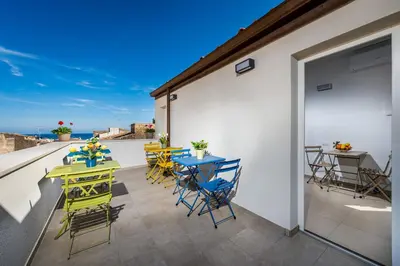 a patio with tables and chairs on a balcony at Affittacamere Nanà in Castellammare del Golfo