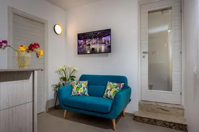 a blue chair in a living room with a tv at Affittacamere Nanà in Castellammare del Golfo
