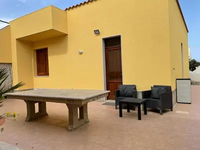 a table and two chairs in front of a yellow building at Appartamento Sunrise in San Vito lo Capo