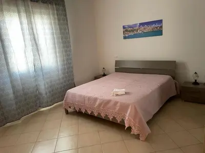 a bedroom with a bed with a pink blanket at Appartamento Sunrise in San Vito lo Capo
