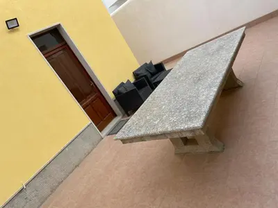 a stone bench in front of a yellow building at Appartamento Sunrise in San Vito lo Capo