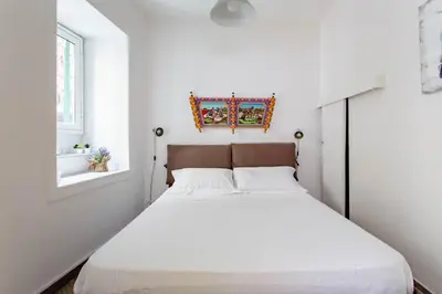 a white bedroom with a bed and a window at Sweet home Ballaro' in Palermo