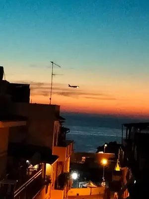 an airplane flying over a city at sunset at Le Lanterne di Terrasini in Terrasini