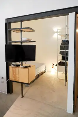 a living room with a tv and a desk with a bed at Mediterranea - Piccola Dimora per Viaggiatori in Castellammare del Golfo