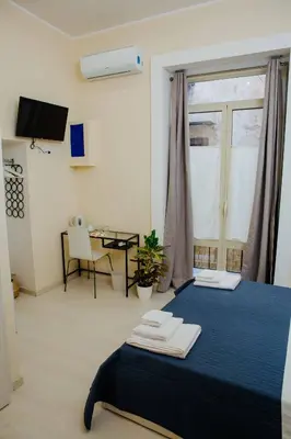 a room with a bed with a table and a window at Calamarina Centro in Palermo