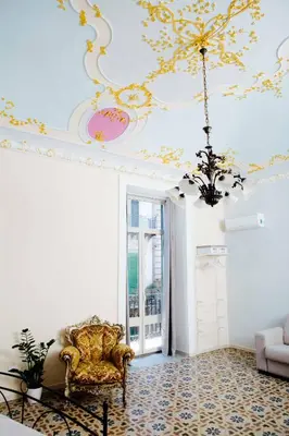 a living room with a ceiling with a chandelier at Calamarina Centro in Palermo
