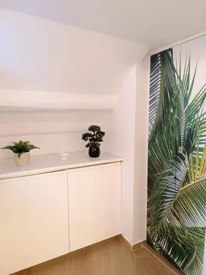 a white room with two potted plants on a white cabinet at Diatomea in Palermo