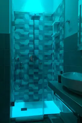 a bathroom with a glass shower with a blue light at B&B Angolo83 Palermo centro in Palermo