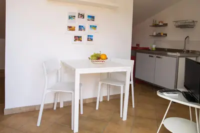a kitchen with a white table and chairs in a room at Boa Vista San Vito - Area Fitness, Barbecue Area, Tennis Court in San Vito lo Capo