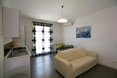 a living room with a couch and a kitchen at Boa Vista San Vito - Area Fitness, Barbecue Area, Tennis Court in San Vito lo Capo