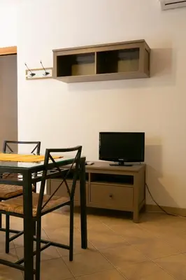 a dining room with a table and a television on a desk at Boa Vista San Vito - Area Fitness, Barbecue Area, Tennis Court in San Vito lo Capo