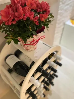 a vase with flowers on a table with wine bottles at Casa vacanza toledo in Partinico