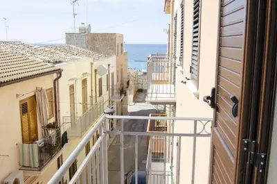 an alley with balconies and the ocean in the background at Solemare Casa Vacanze in Castellammare del Golfo