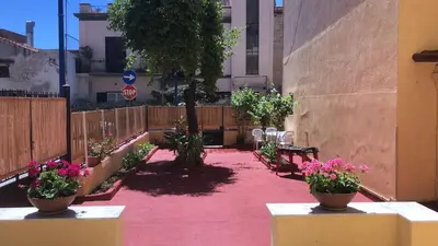 a patio with tables and flowers in a courtyard at Josh's House Mondello in Mondello