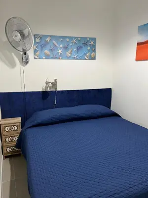 a blue bed in a bedroom with a fan at Josh's House Mondello in Mondello