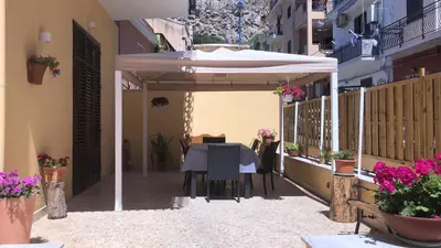 a patio with a table and a white umbrella at Josh's House Mondello in Mondello