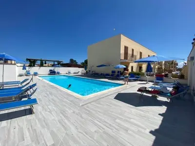 a swimming pool with chairs and umbrellas next to a building at Casa Vacanze Costanza in San Vito lo Capo