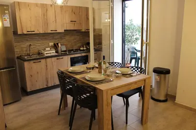 a kitchen with a wooden table and some chairs at Zisa Home ai Cantieri Culturali con Patio Privato - vicino centro storico - No ZTL in Palermo