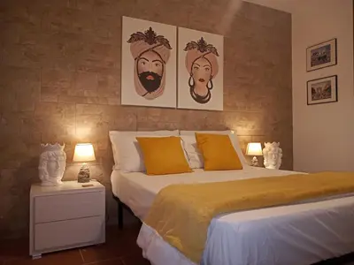 a bedroom with a bed and two pictures on the wall at Zisa Home ai Cantieri Culturali con Patio Privato - vicino centro storico - No ZTL in Palermo