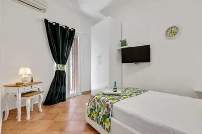a bedroom with a bed and a desk and a television at GuestHost - Vucciria Market Apartment with Balconies in Palermo