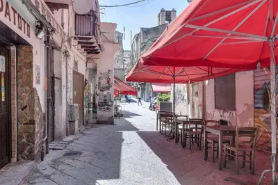 a red umbrella and tables and chairs on a street at GuestHost - Vucciria Market Apartment with Balconies in Palermo