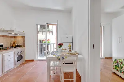 a white kitchen with a table and chairs in it at GuestHost - Vucciria Market Apartment with Balconies in Palermo