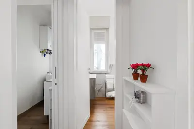 a hallway with white walls and a white door with flowers at GuestHost - Residenza dei Poeti - Roomy and Modern Flat in Palermo