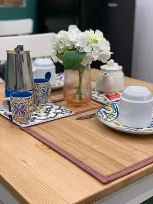 a wooden table with plates and a vase of flowers at Apartament la Lumaca Kalsa in Palermo