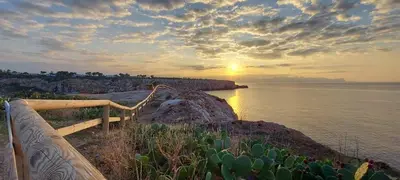 a sunset over a body of water with a bench at Il moro - Casa Vacanze in Terrasini