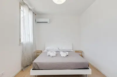 a white bedroom with a bed with two white towels at GuestHost - BallarHost - Ballarò Market Terrace Apartment in Palermo
