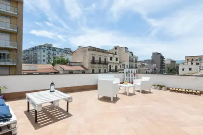 a patio with white chairs and tables on a roof at GuestHost - BallarHost - Ballarò Market Terrace Apartment in Palermo