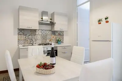 a kitchen with a table with a bottle of wine and a basket of fruit at HouseStation in Palermo